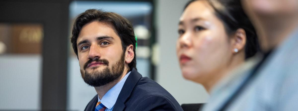 Two students in business attire listen during a presentation.