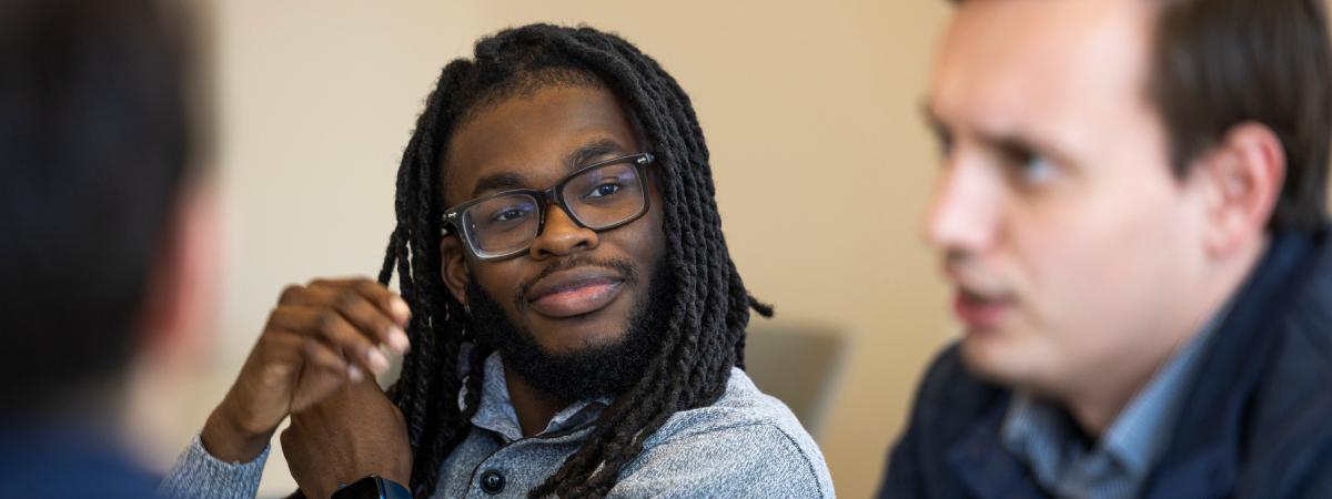 A close-up of a male student listening intently during a discussion with a classmate.