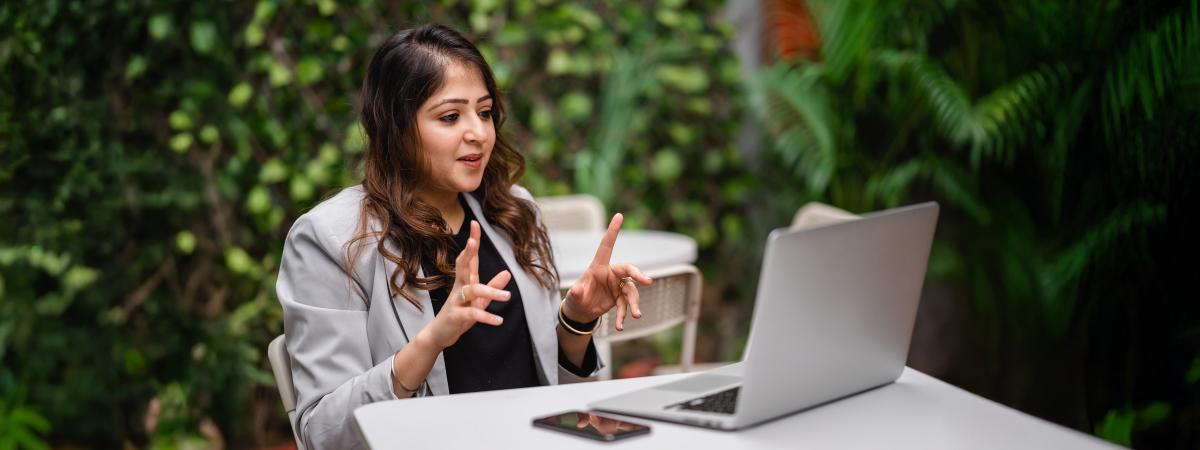A student sits outside while taking an online course.