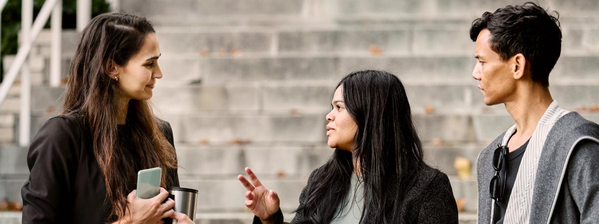 Three young adults conversing on a set of wide outdoor stone steps.