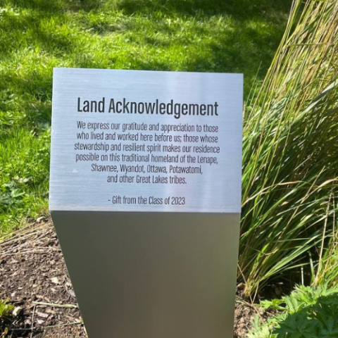 Text on land acknowledgement marker reading "We express our gratitude and appreciation to those who lived and worked here before us, those whose stewardship and resilient spirit makes our residence possible on this traditional homeland of the Lenape, Shawnee, Wyandot, Ottawa, Potawatomi, and other Great Lakes tribes"