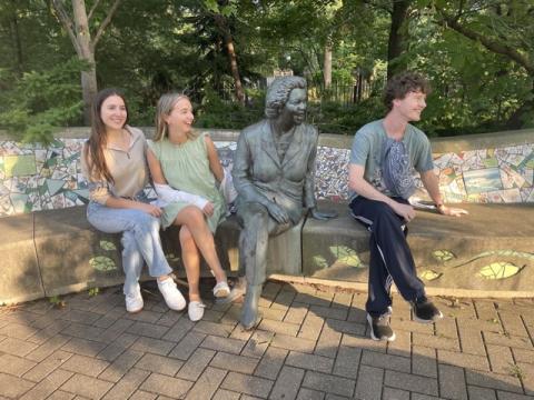 Students pose with a statue on campus