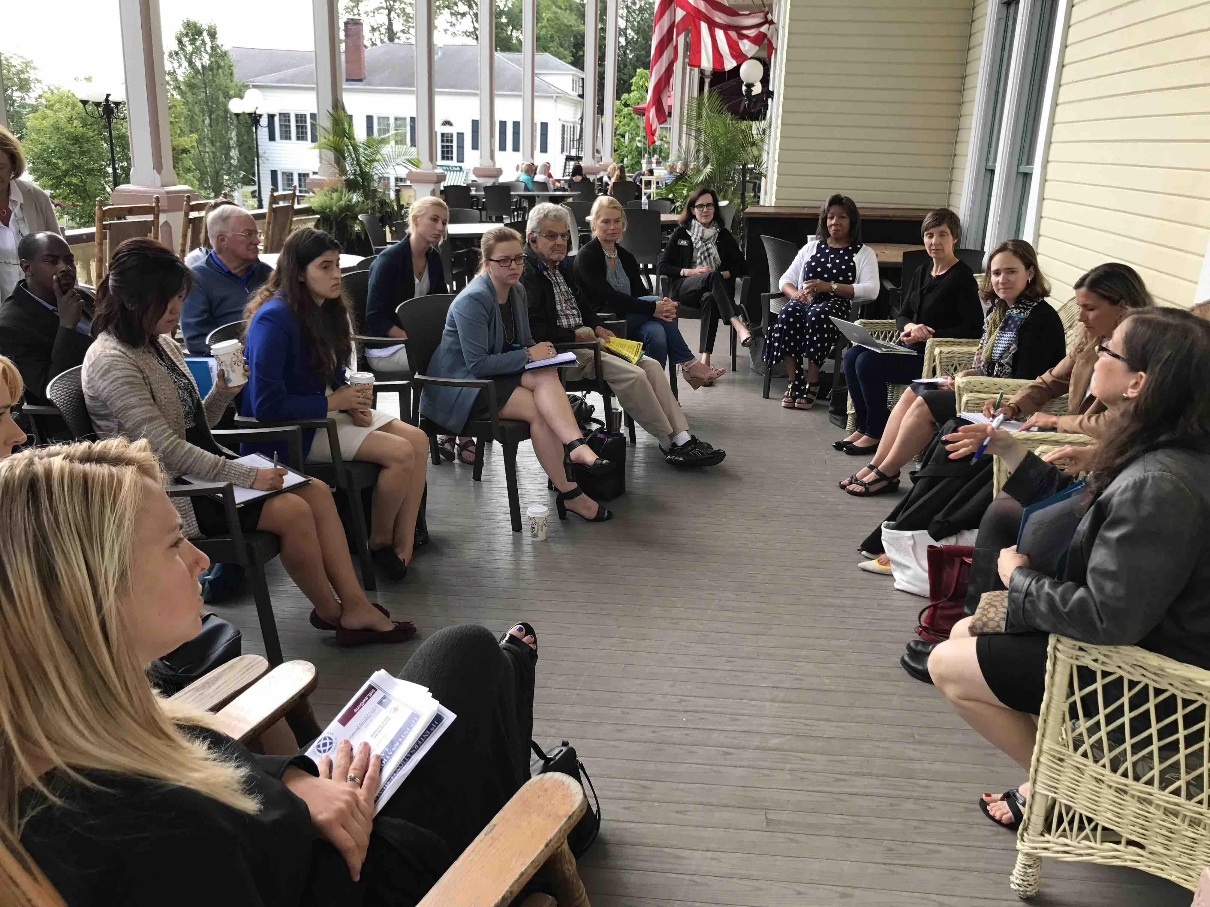 Chautauqua roundtable event in 2023, attendees gather on a porch to listen to panelists discuss 
