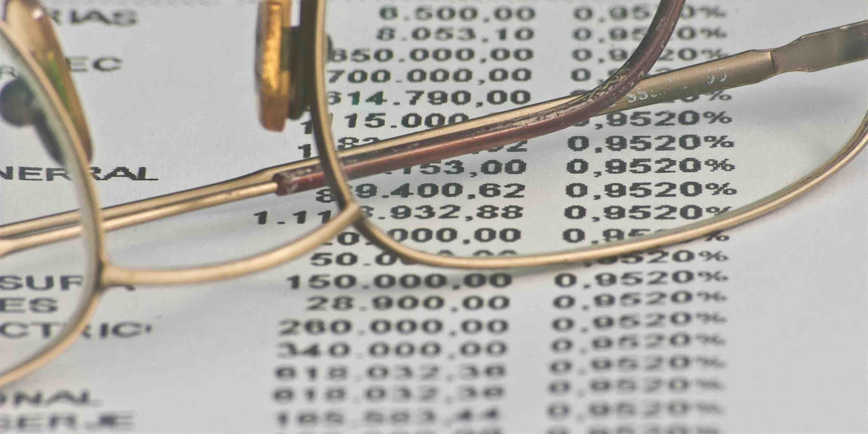 close up shot of wire-rimmed glasses sitting on top of a spreadsheet of numbers