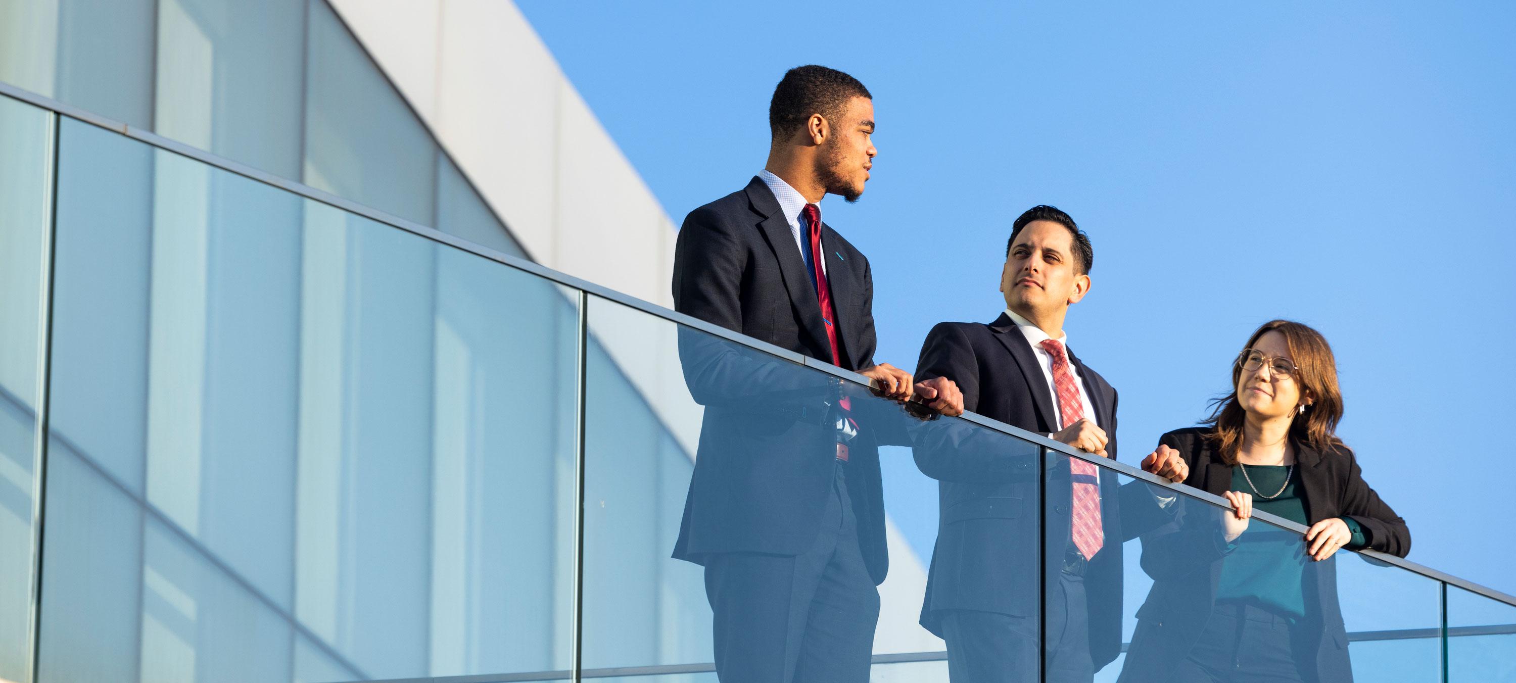 Three students standing outside on a balcony