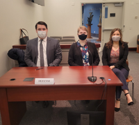 Three masked students sitting at a table for Costello mock trial
