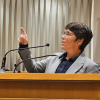 Kati Kovacs presenting in the Moot Courtroom, standing behind the podium and gesturing with her right hand.