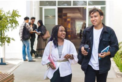 Two students hold their books and supplies as they walk away from the lecture hall.