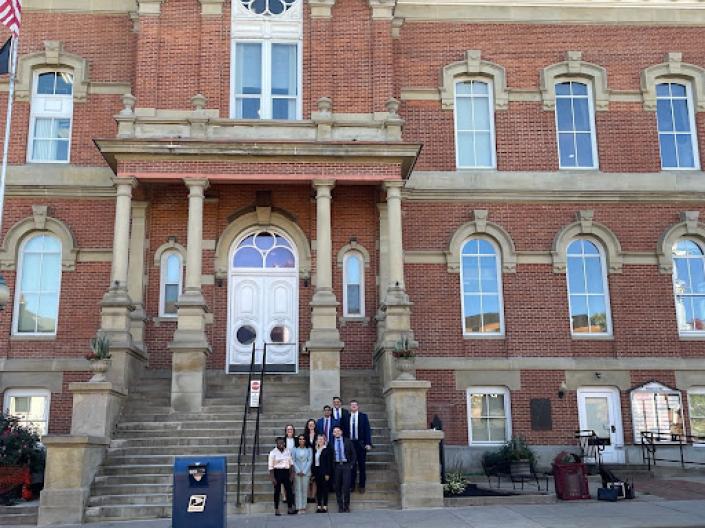 a group of nine individuals standing at the bottom on the stairs in front of Athens County Courthouse.