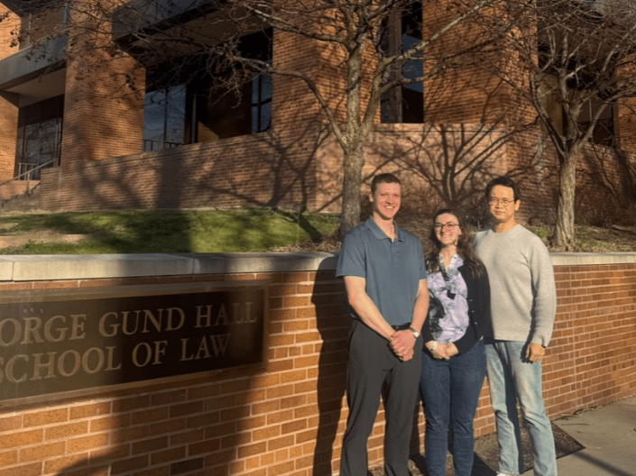 Patent Application team outside of the law school in front of the sign reading "George Gund Hall" 