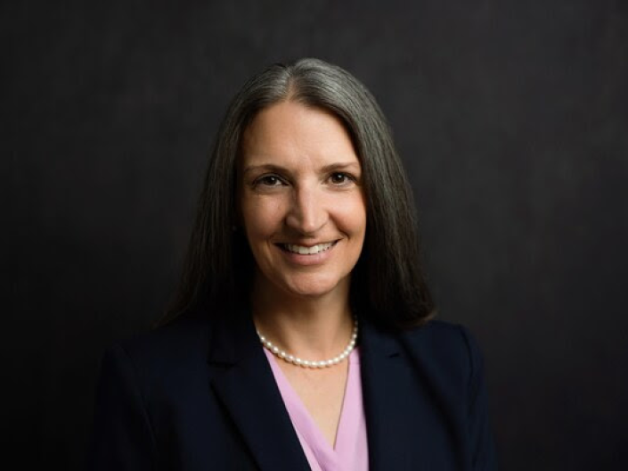 Colleen Batcheler headshot in front of dark grey background