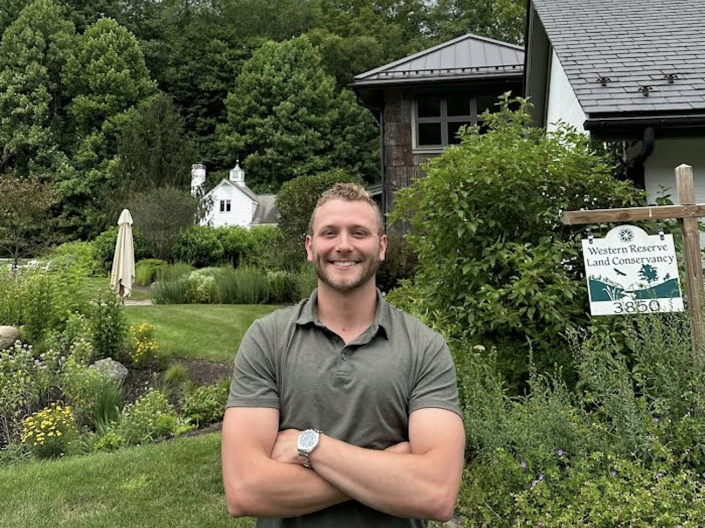 Logan Byler standing in front of a sign for the Western Land Conservancy