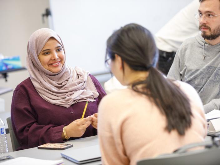 Three students work together in class while smiling.