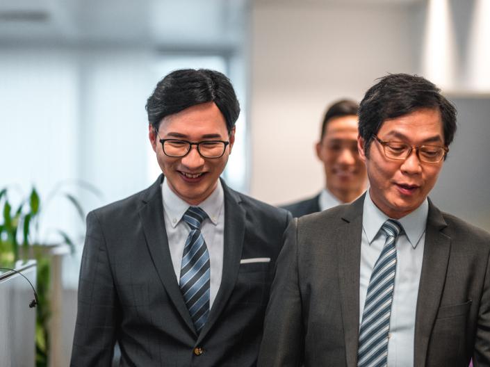 Three lawyers smile as they walk together.