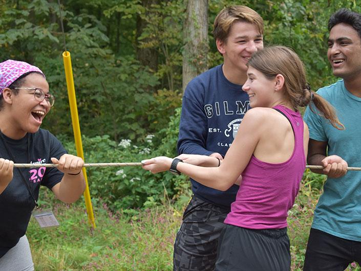 Group of students laughing outdoors and pulling a rope