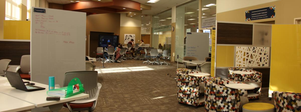 View of the Collaboration Commons with tables, chairs, and whiteboards.