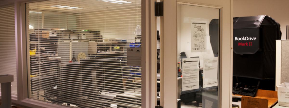 View through blinds and door into a lab with digitization equipment