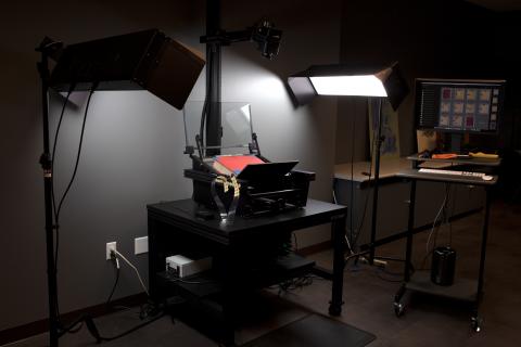 A Phase One Reprographic System setup with lights, ready to photograph a book resting in a book cradle.