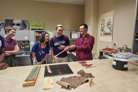 Students gathered around a preservation officer learning about bookbinding.