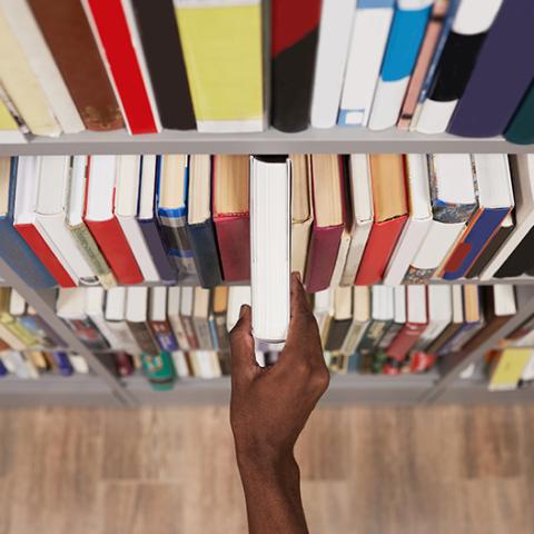 Hand taking a book off a shelf