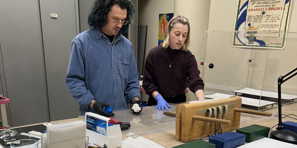 Two preservationists work at a table at Kelvin Smith Library