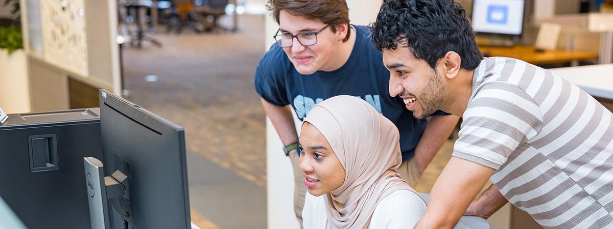 Three students work on a computer at Kelvin Smith Library.