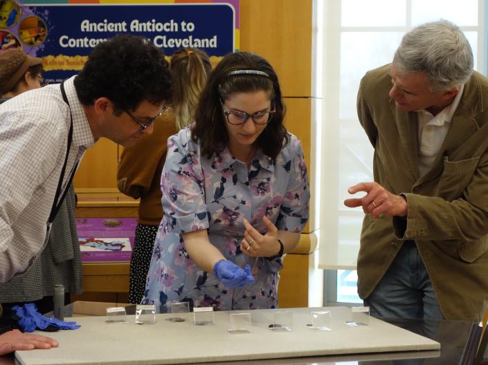 Student holds coin while two onlookers ask questions at Kelvin Smith Library.