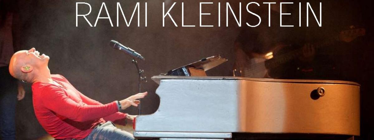 Photo of Rami Kleinstein leaning back and playing the piano on stage