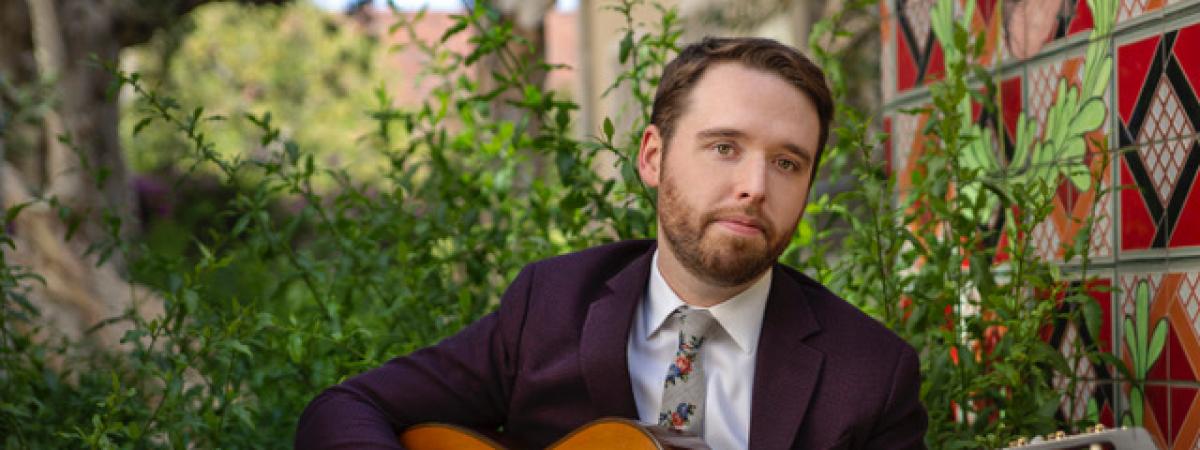 Headshot of Colin Davin holding a guitar