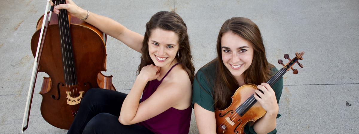 Renovare duo sitting on ground with instruments