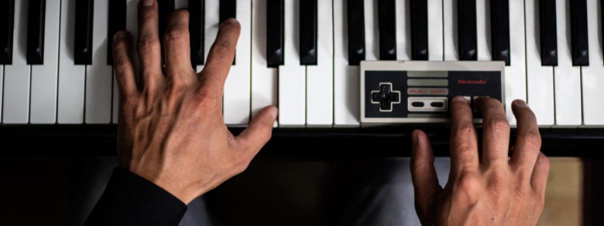 hands on piano keyboard with one hand on a Nintendo controller