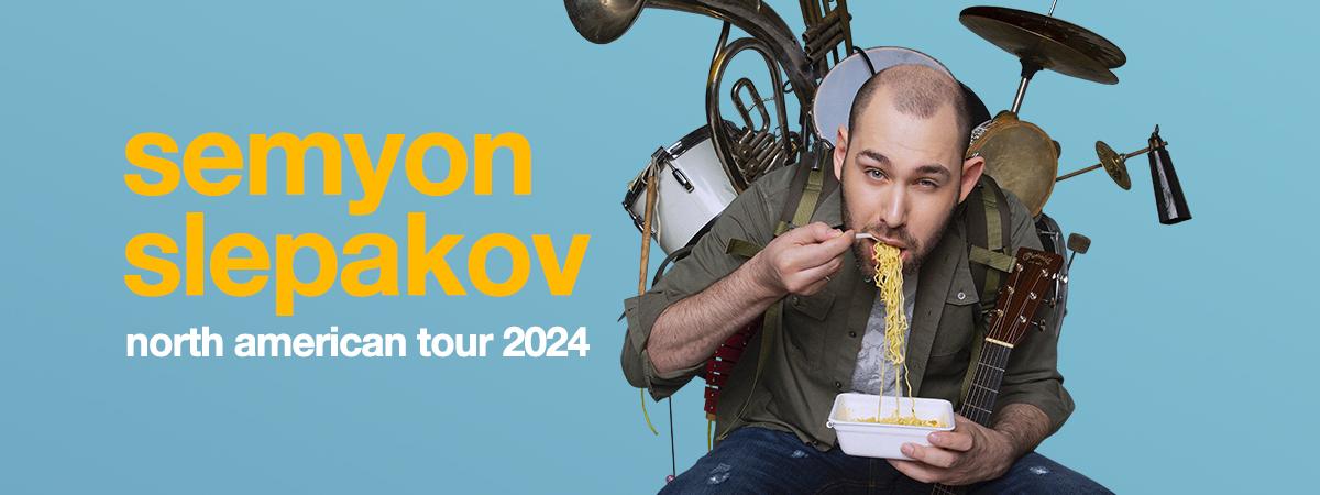 Semyon Slepakov sits, eating pasta with instruments strapped to his back