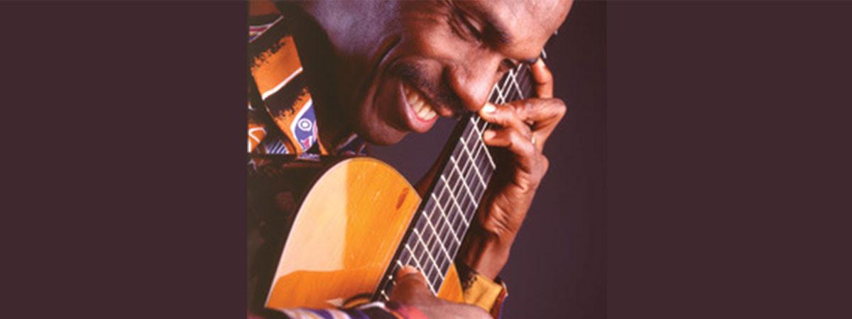 Celso Machado, smiling with guitar held close