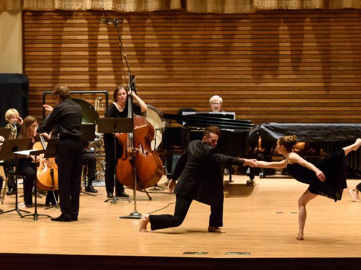 Large group of people on stage and half have instruments and are playing and half are dancing