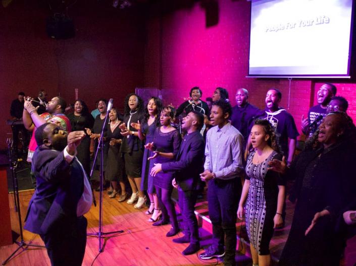 Group of people standing on a small stage singing