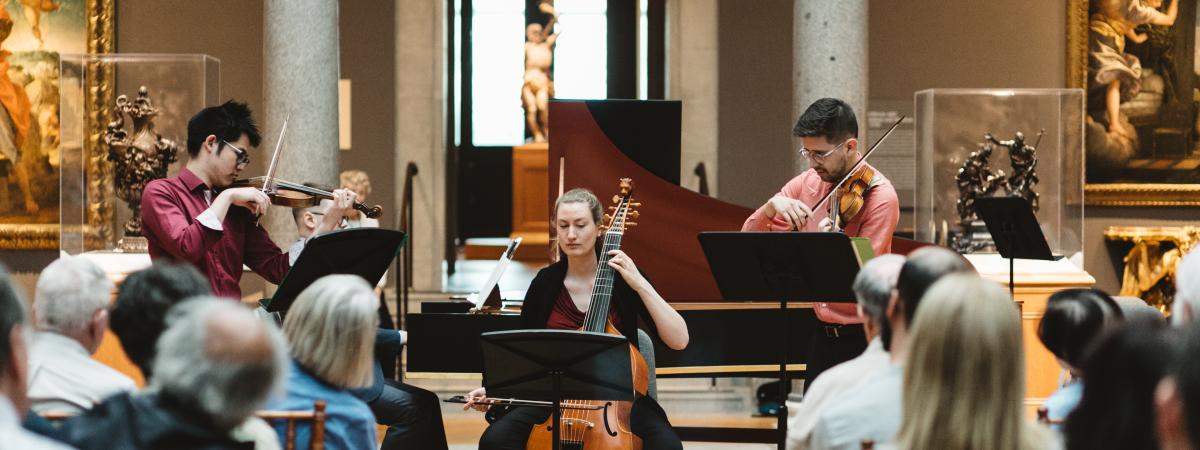 Baroque artists playing (l-r) violin, cello, violin