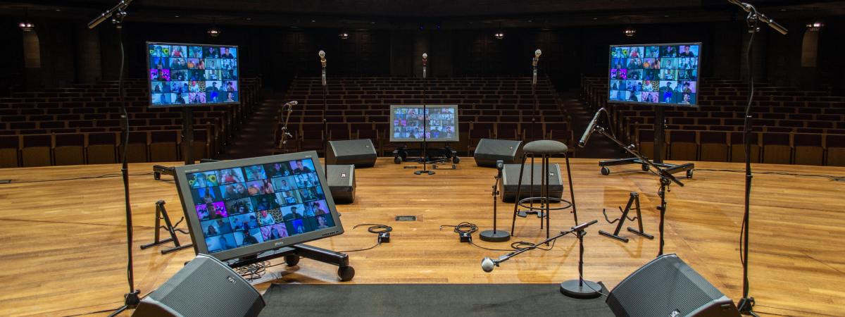 MPAC's stage facing seats, with drum carpet, an amp on each side, and 3 screens