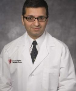 Portrait of Sanjay Ahuja posing in a University Hospital doctors coat.