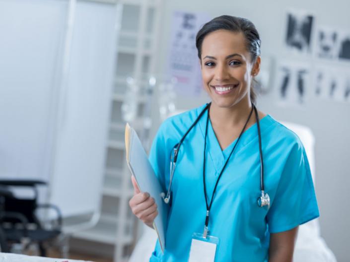 A nurse smiling in her blue scrubs. 