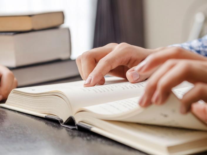Hands turning pages in a textbook.