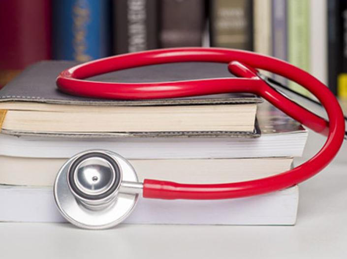 Stethoscope draped across books on a desk