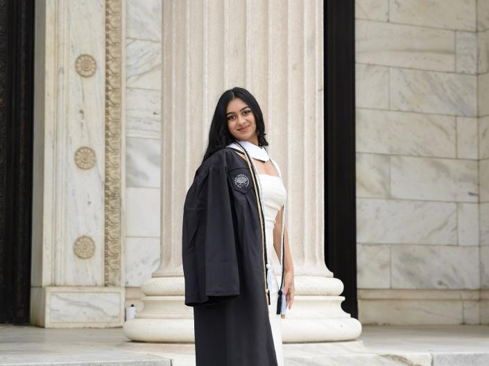Ishita in her graduation regalia standing on stairs