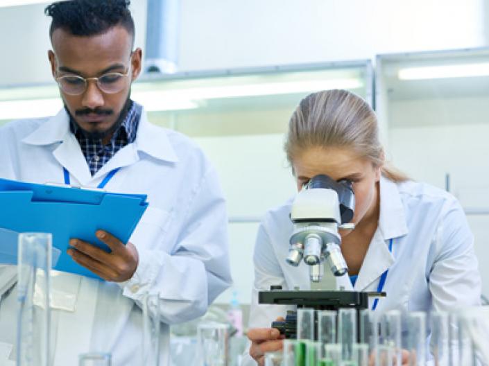 Two medical students working in a lab with a microscope