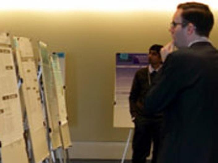 Man looking at display posters with another man in the background