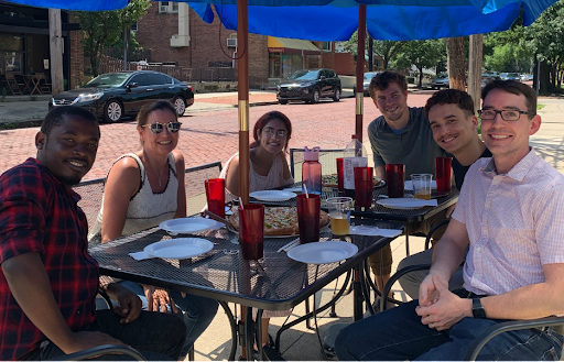 Group of men and women around a patio table outside eating lunch