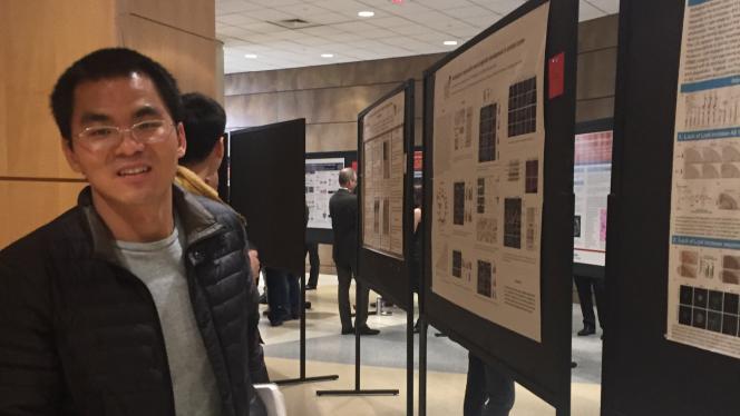 A postdoctoral fellow next to a poster