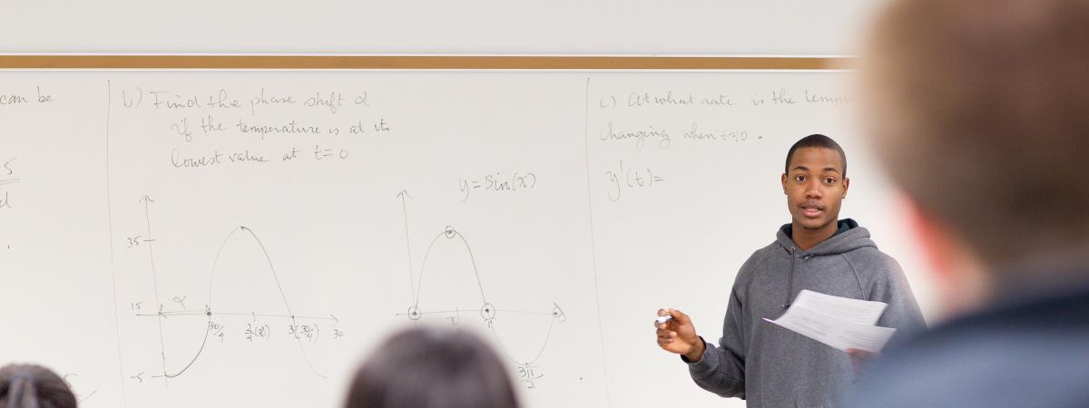 Student teaching students at a white board