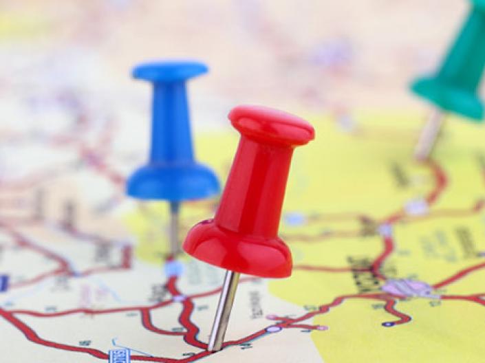 Image of map with red roads showing and red, blue and green push pins sticking out