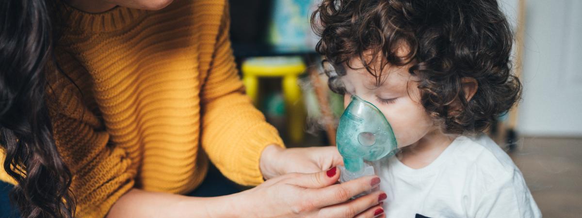 Close up of a mother helping a young child to use a nebulizer