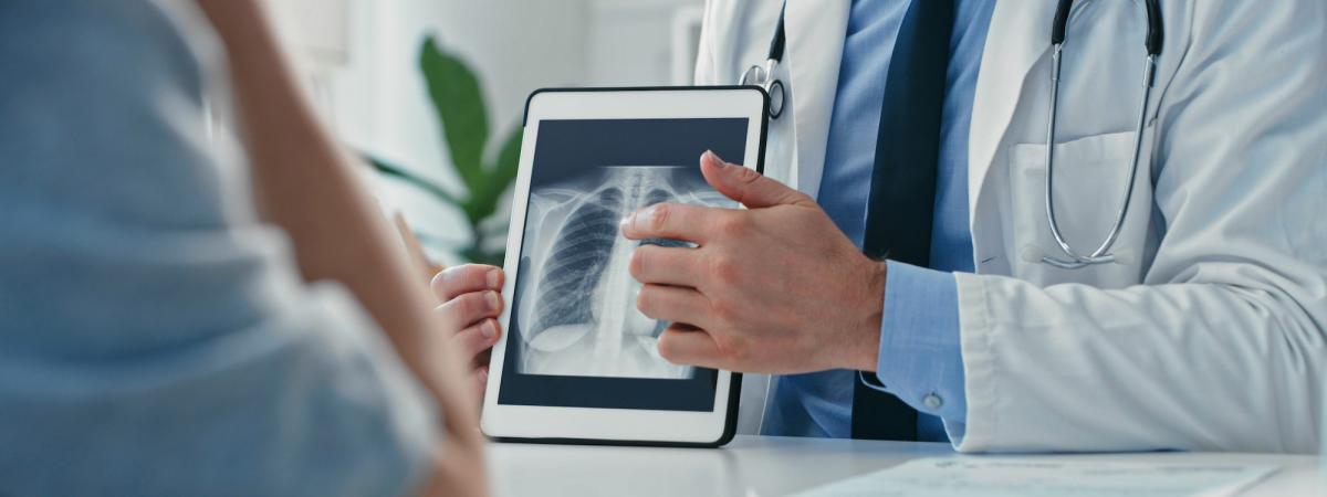Close up of a doctor sitting with a patient and showing x-rays on a digital tablet